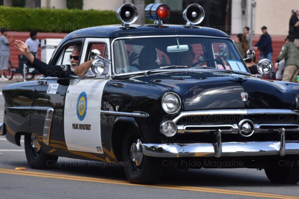 Man Waving Out of An Old School Police Car